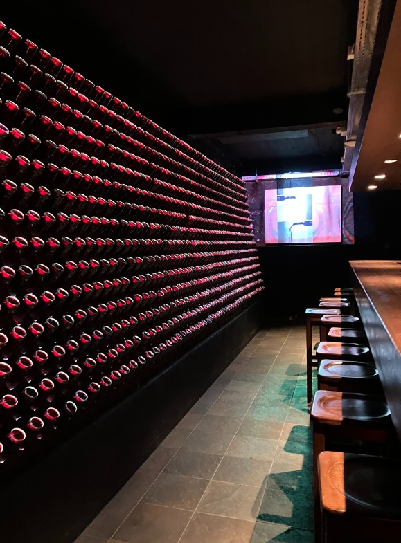A wall of red wine bottles and a wooden tasting bar