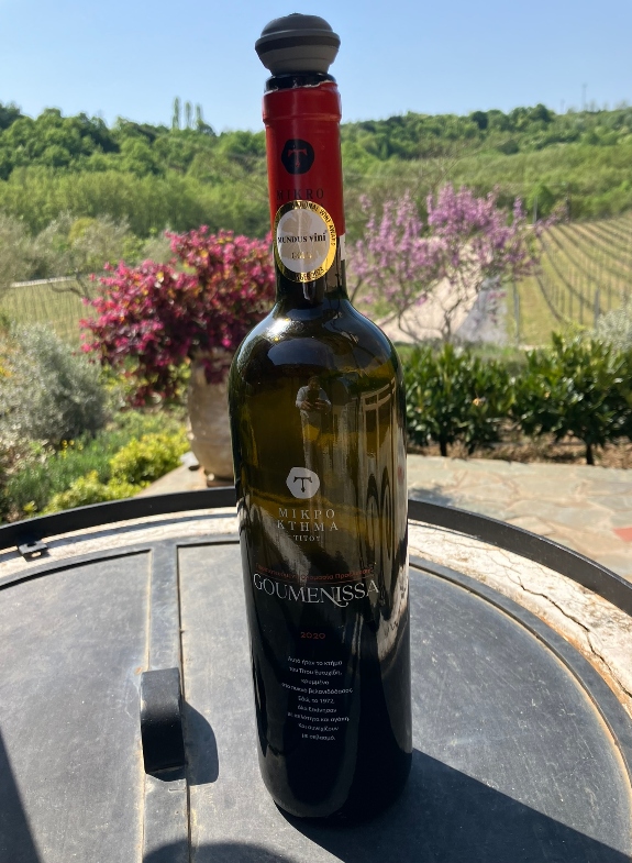 Red Goumenissa wine bottle and spring flowers backdrop