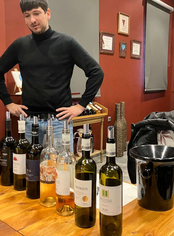 The winemaker stands in front of 10 bottle of wine that have been presented to the wine tasting